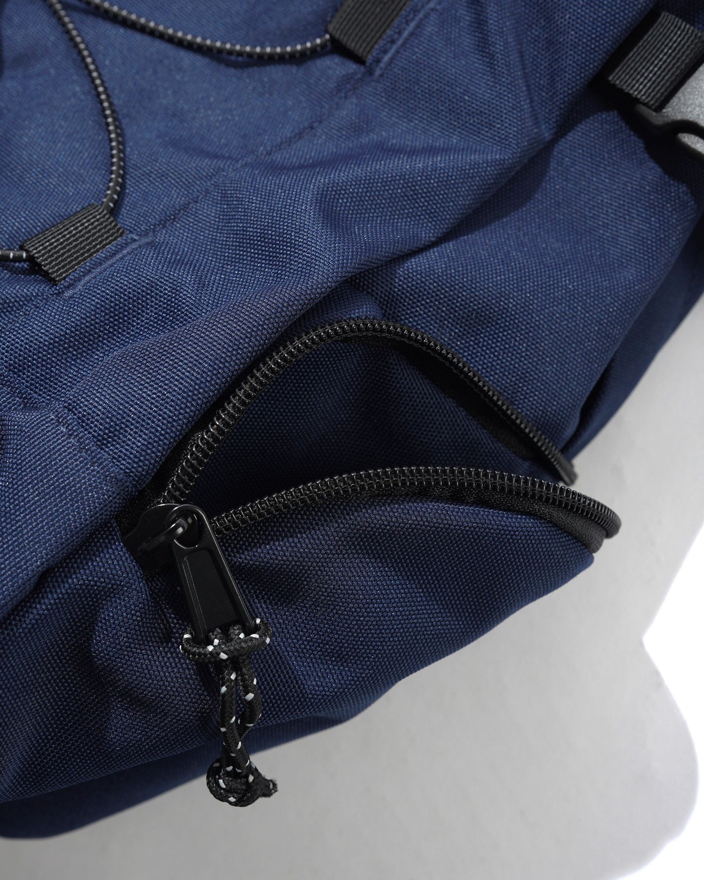 Close-up of a navy blue backpack with black zippers on a white background