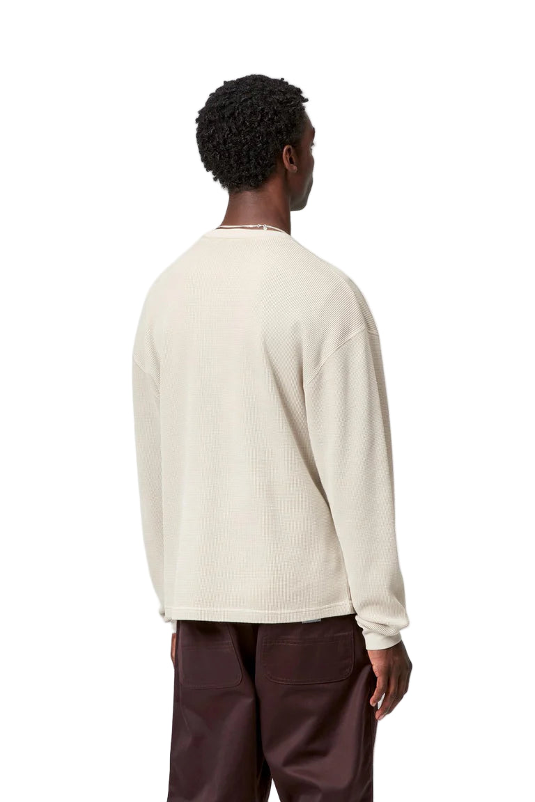 Person wearing a cream sweater and brown pants on a white background