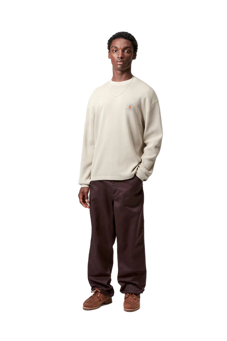 Man wearing a beige sweater and brown pants on a white background