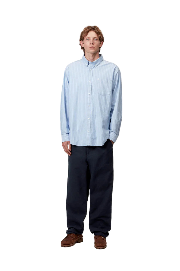 Person wearing a light blue checkered shirt and dark pants on a white background