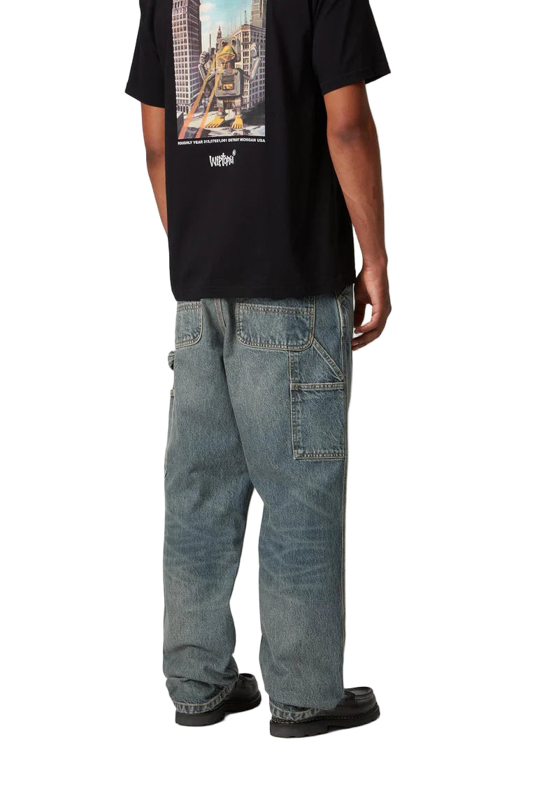Person wearing a black t-shirt with a graphic design and blue jeans on a white background