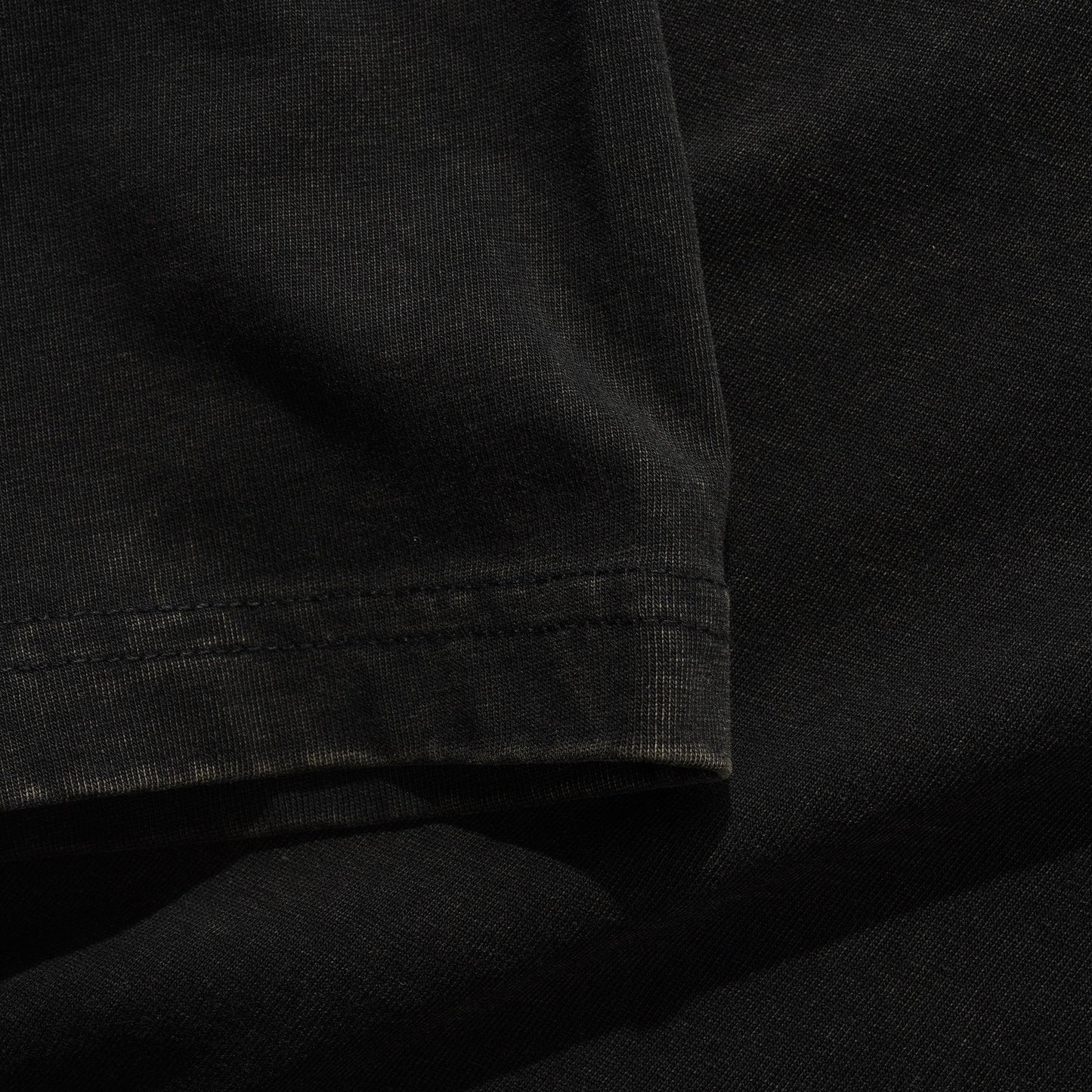 Close-up of a black t-shirt with visible stitching detail.