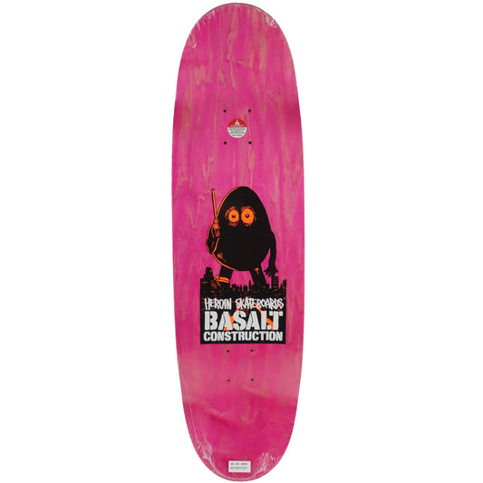 A pink skateboard deck featuring a black cartoon character holding a paintbrush and a large Basalt Construction logo graphic near the bottom.