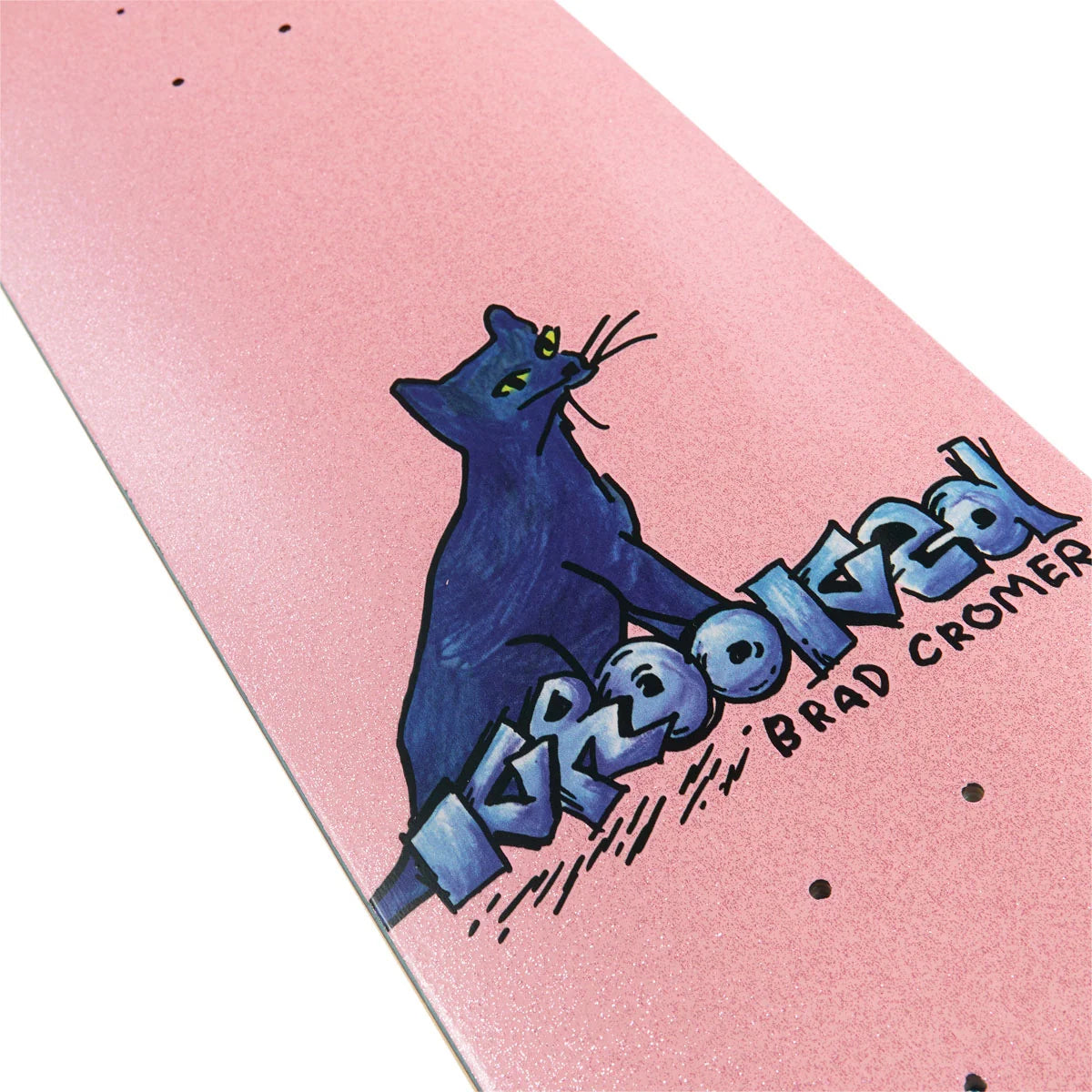 A close-up of a skateboard deck with a glittery pink background, featuring a blue cat graphic and the text 'krooked' and 'BRAD CROMER'.