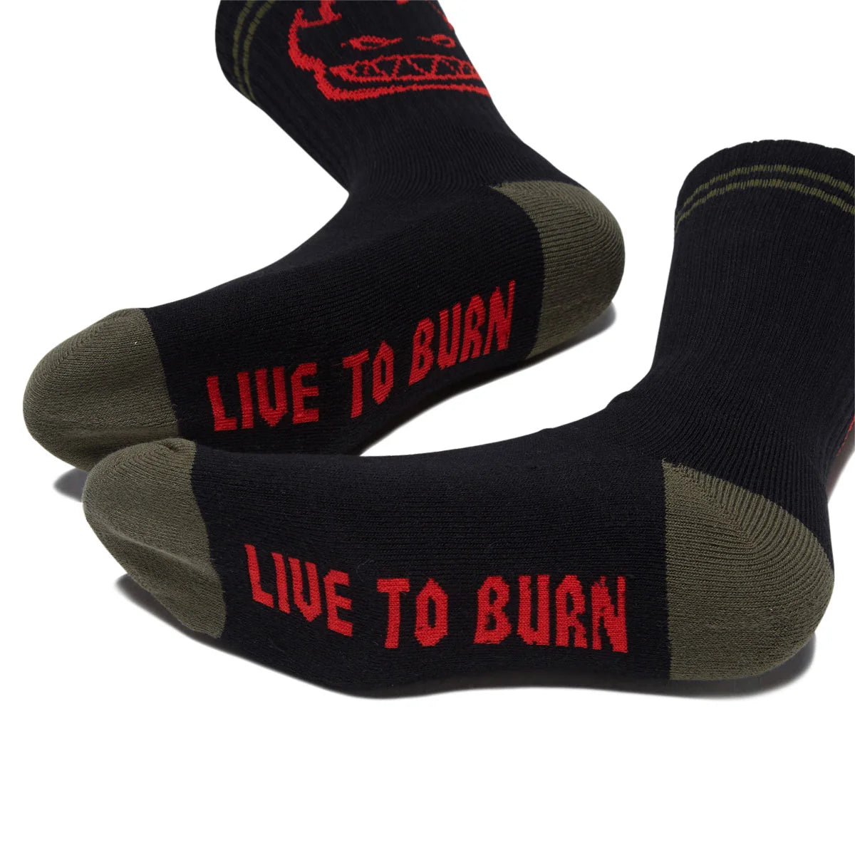 A pair of black crew socks with olive green heels and toes, featuring the red text 'LIVE TO BURN' and a red skull graphic on the upper leg, displayed on a white background.