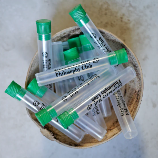 Test tubes with green caps labeled 'Philosophy Club' in a wooden bowl.