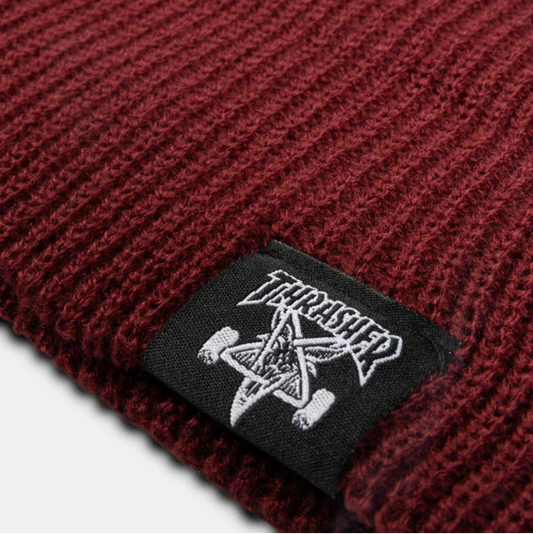 Close-up of a red knit beanie with a branded tag featuring a pentagram and skateboard design.