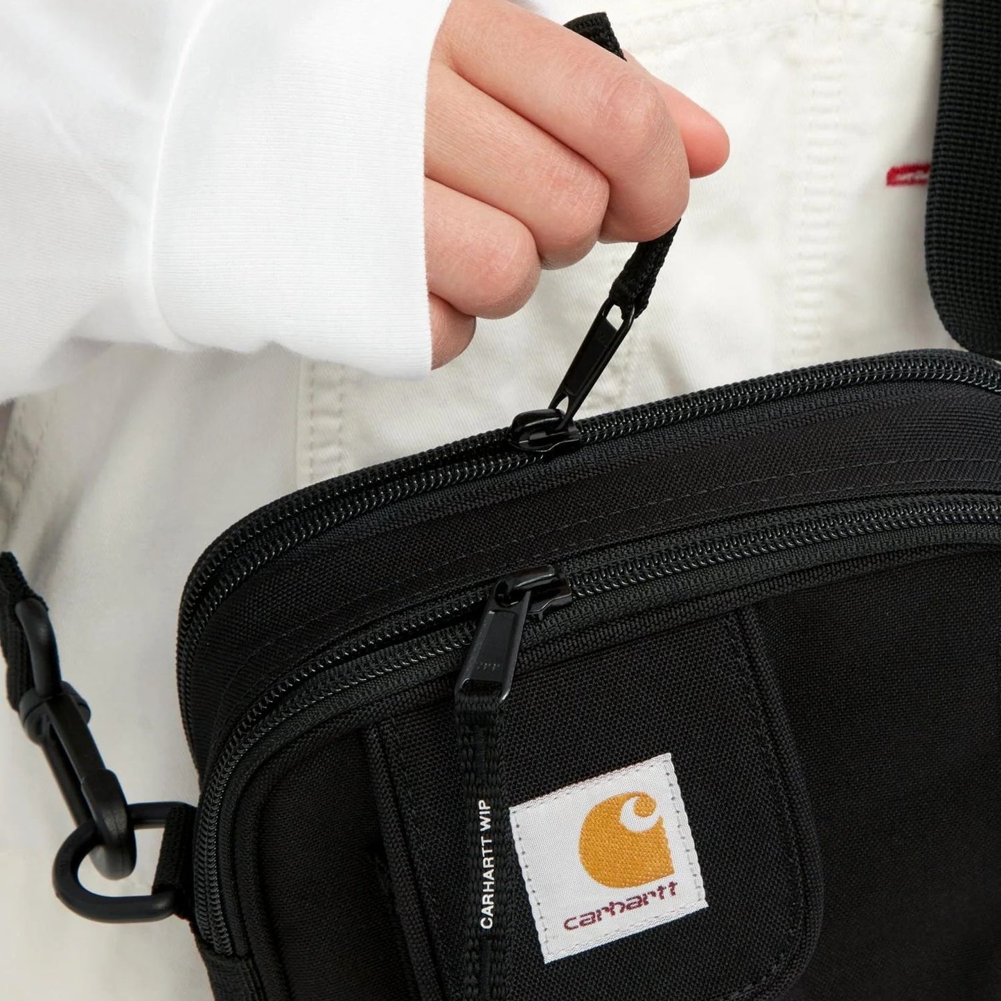 Black Carhartt bag held by a person wearing a white jacket.
