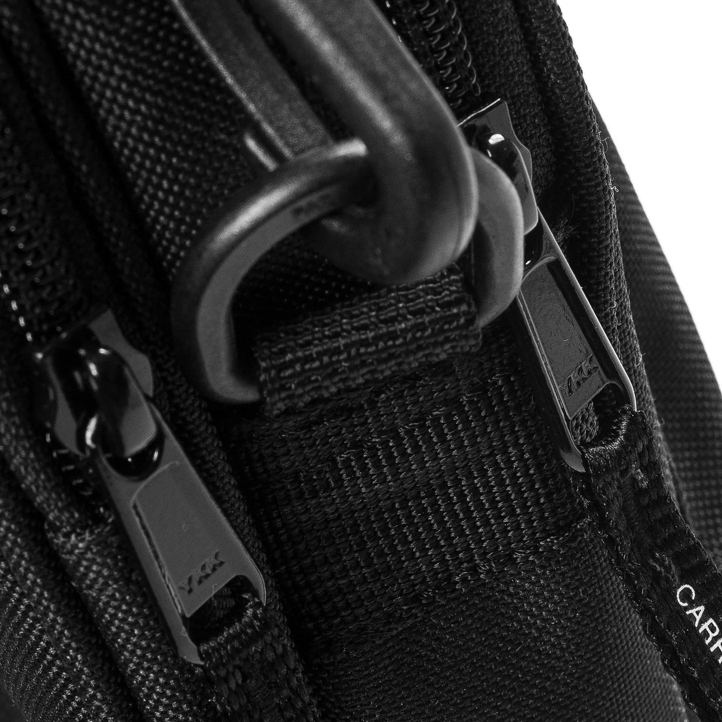 Close-up of a black bag with zippers and straps on a white background