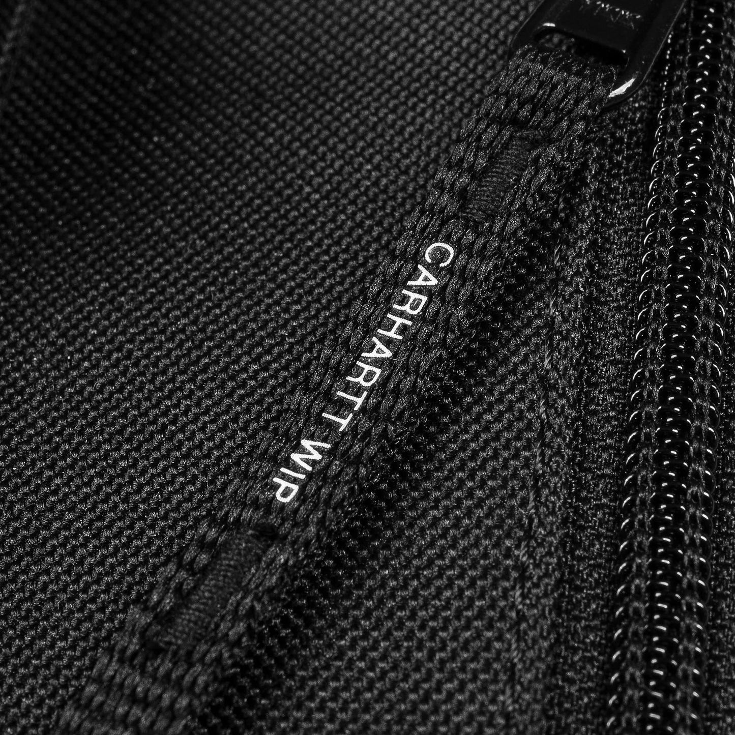 Close-up of a black zippered bag with Carhartt WIP branding.