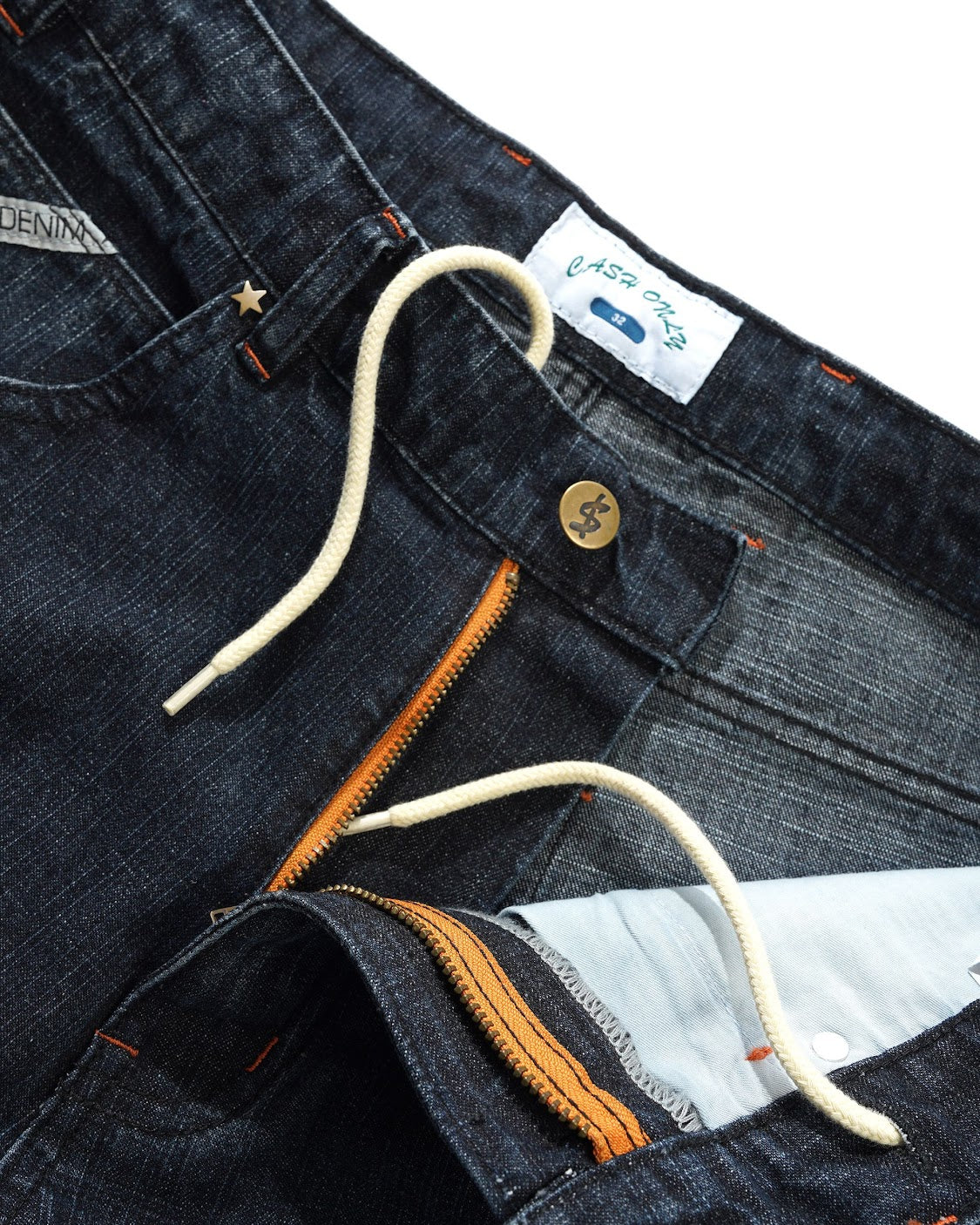 Close-up of dark blue jeans with a brand label and stitching details.