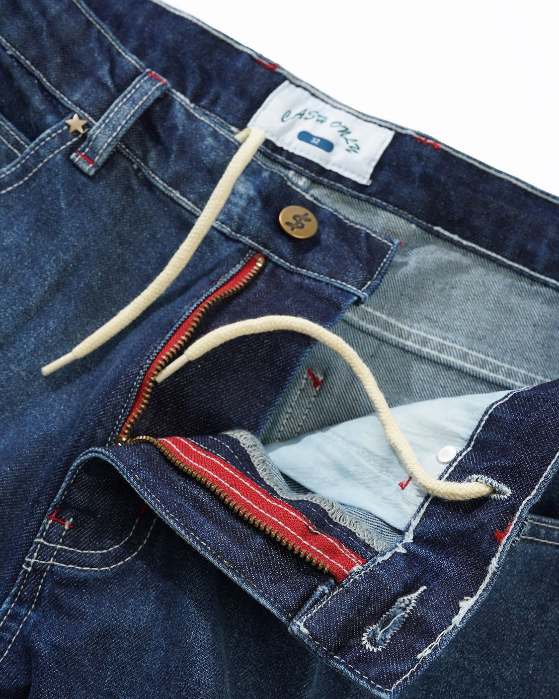 Close-up of blue denim jeans with a brand label and button.