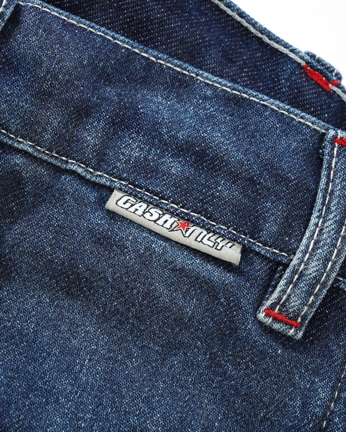 Close-up of a blue denim pocket with a brand label on a white background