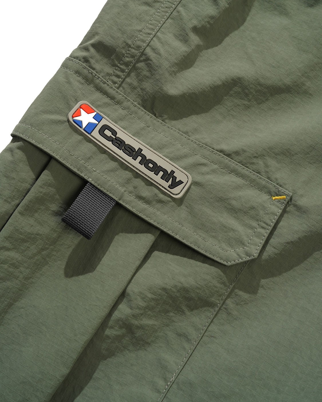 Green pants with a Cashonly logo patch on a white background