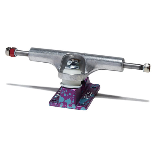 A single skateboard truck with a silver metal hardware body and a purple baseplate featuring blue and teal paint splatter, shown on a white background with a soft shadow.