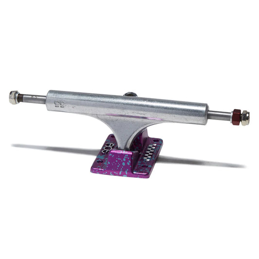 A skateboard truck with a silver metal body and a vibrant purple and blue speckled baseplate, shown on a clean white background.