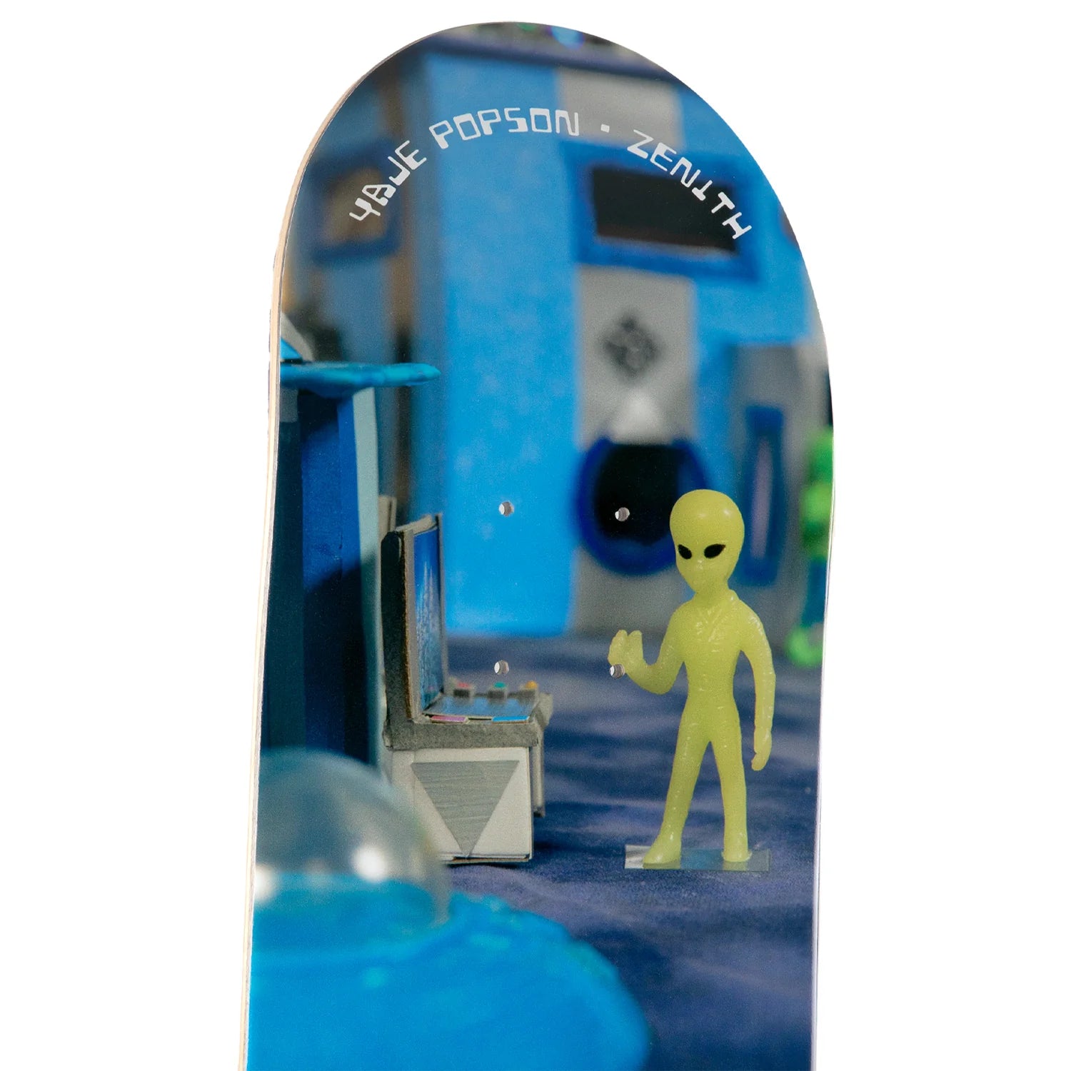 A skateboard deck featuring a printed graphic of a yellow alien standing in front of a blue futuristic room