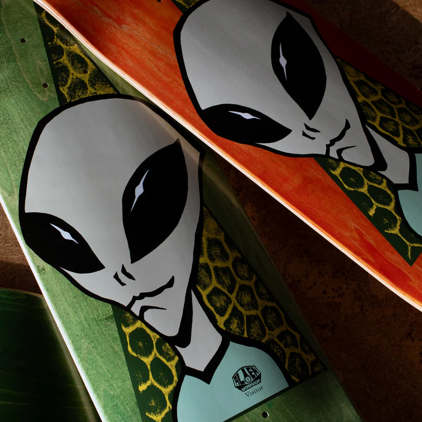 Two skateboard decks with alien graphics on a wooden surface