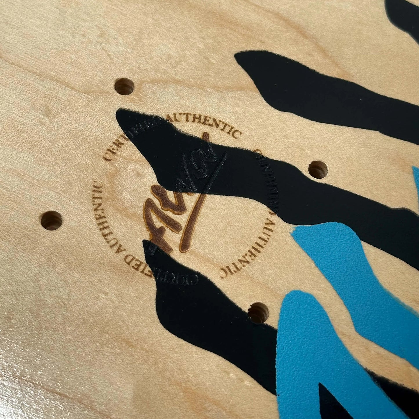 Close-up of a skateboard deck with 'Authentic' branding and black and blue graphics.