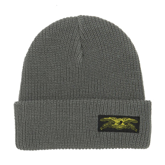 A dark gray ribbed knit beanie hat featuring a black rectangular patch on the front cuff with a yellow embroidered eagle logo 