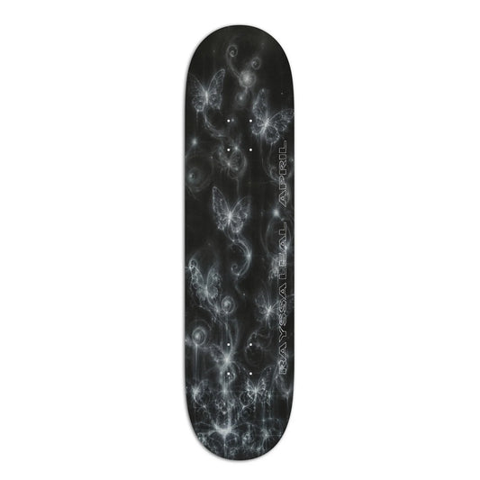 A skateboard deck with a black background featuring a white and gray cosmic design of swirling nebulae and glowing butterflies, with the brand name 'rayssa leal april' printed vertically on the right side.