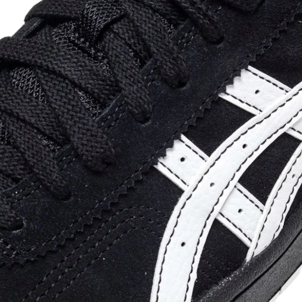 Close-up of a black sneaker with white laces and a white logo on a black background