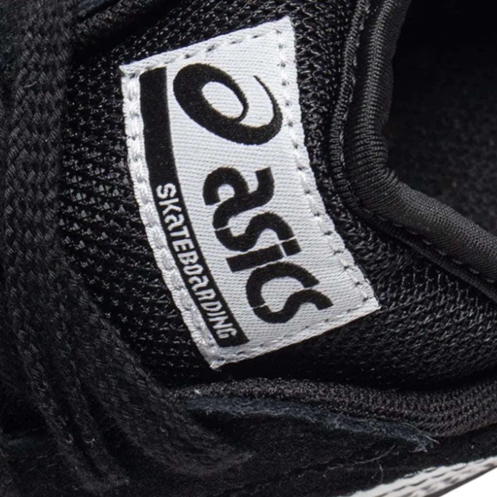 Close-up of a black sneaker with a visible Asics logo on a dark background