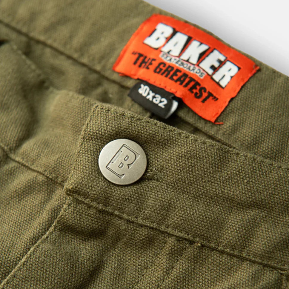 Close-up of green pants with a Baker brand label and button.