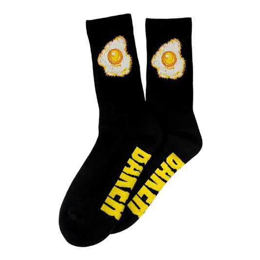 A pair of black crew socks featuring a graphic of a fried egg on the upper cuff and bold yellow text reading 'DANGER' printed vertically on the sole, displayed against a solid white background.