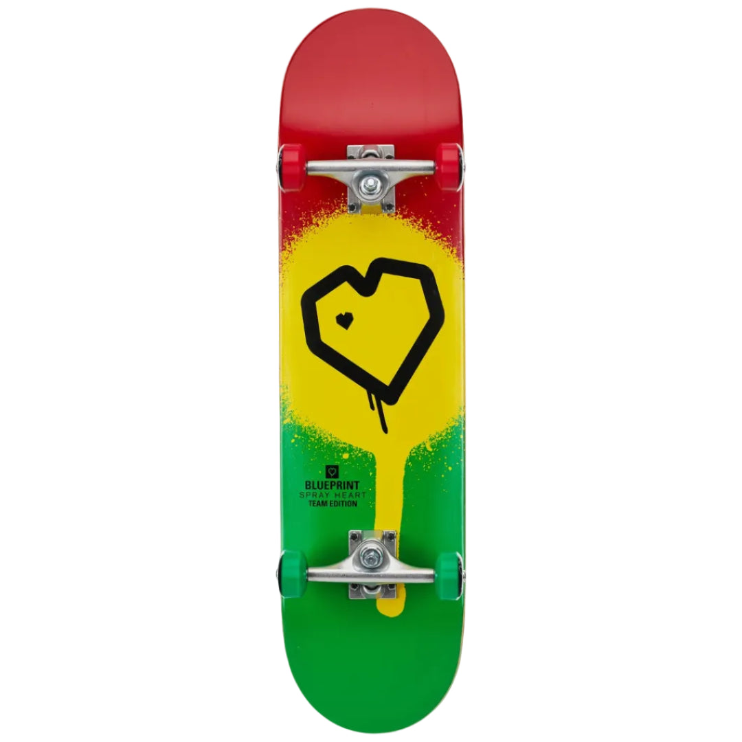 A skateboard deck featuring a red, yellow, and green gradient design with a black heart logo in the center. The deck includes visible silver trucks and green wheels, set against a plain white background.