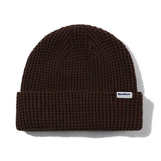 Brown knit beanie with a brand logo on a white background