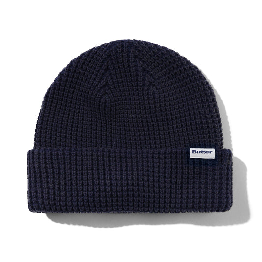 Navy blue knit beanie with a brand label on a white background