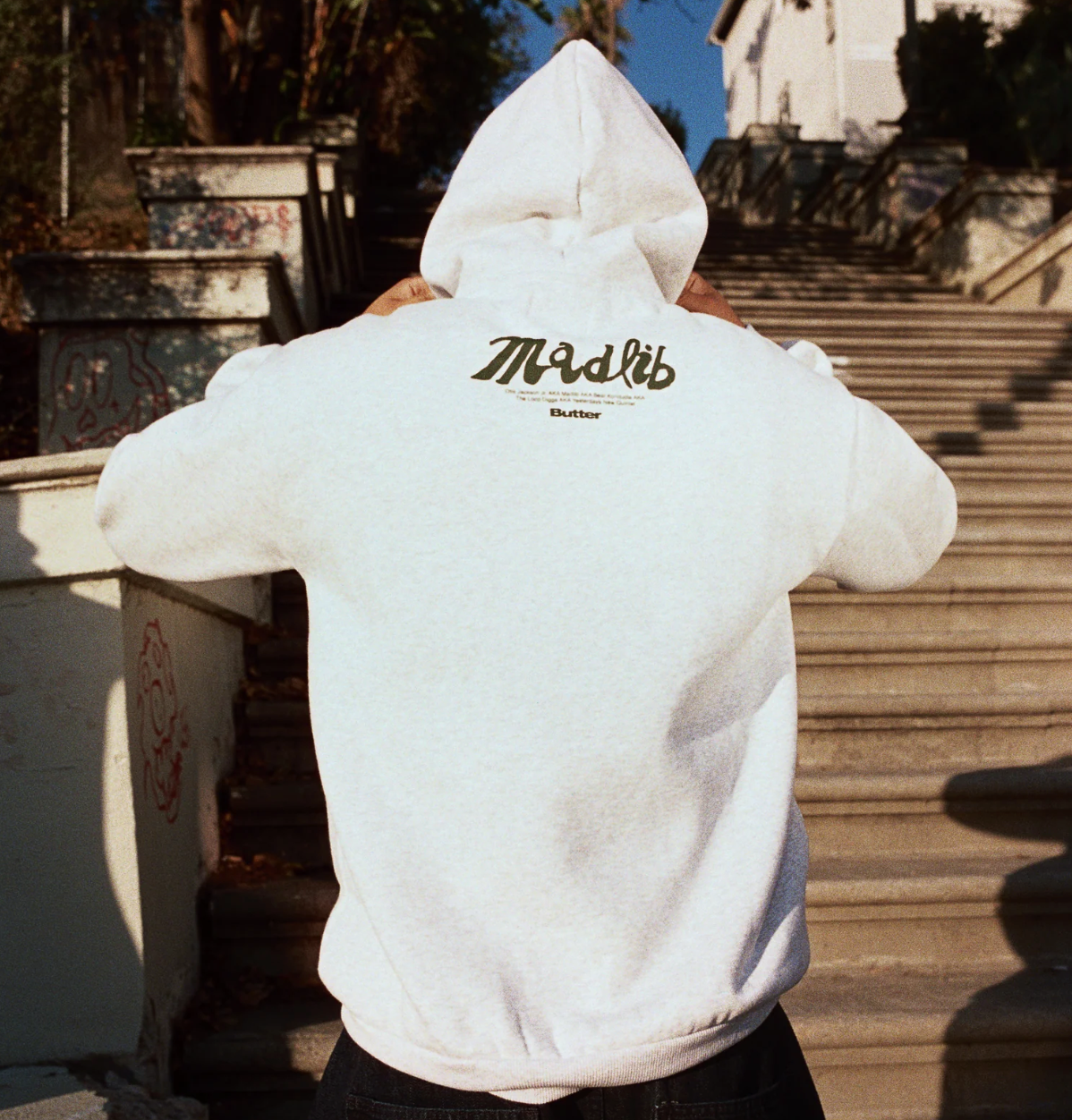 Person wearing a white hoodie with 'Madlib' logo on the back, standing outdoors.