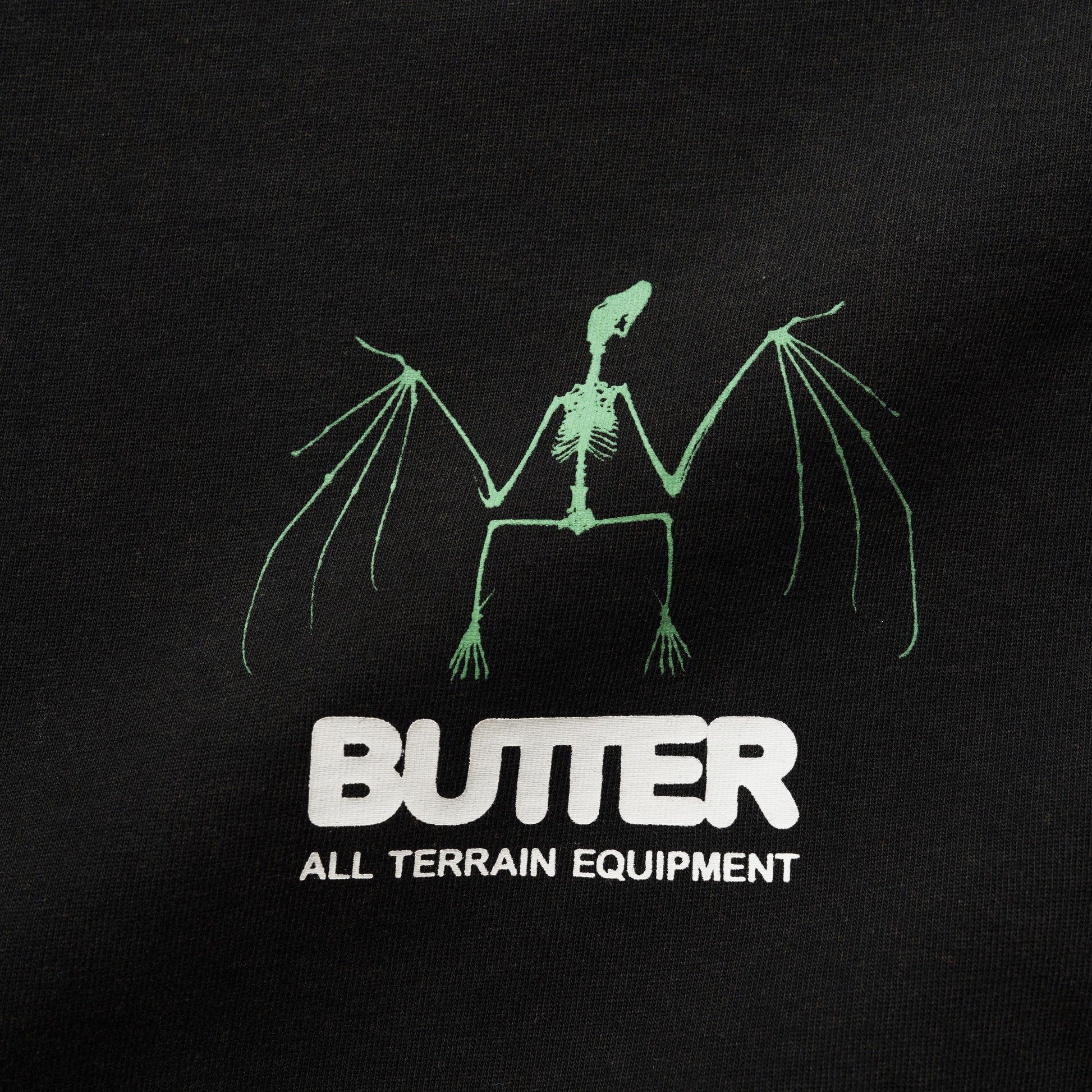 Black t-shirt with green skeleton design and 'Butter All Terrain Equipment' text on a black background