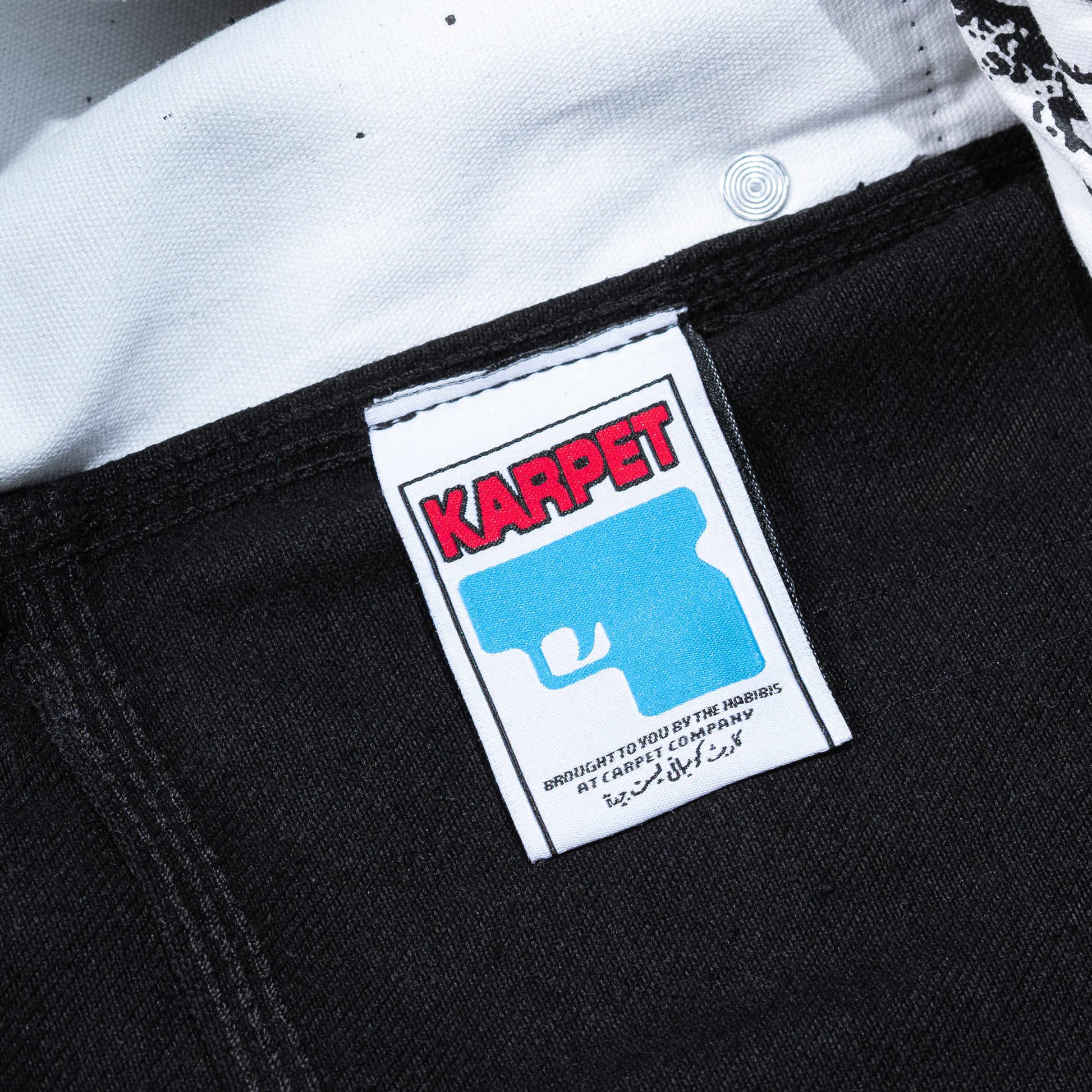 Close-up of a Karpet label on a black garment with white background