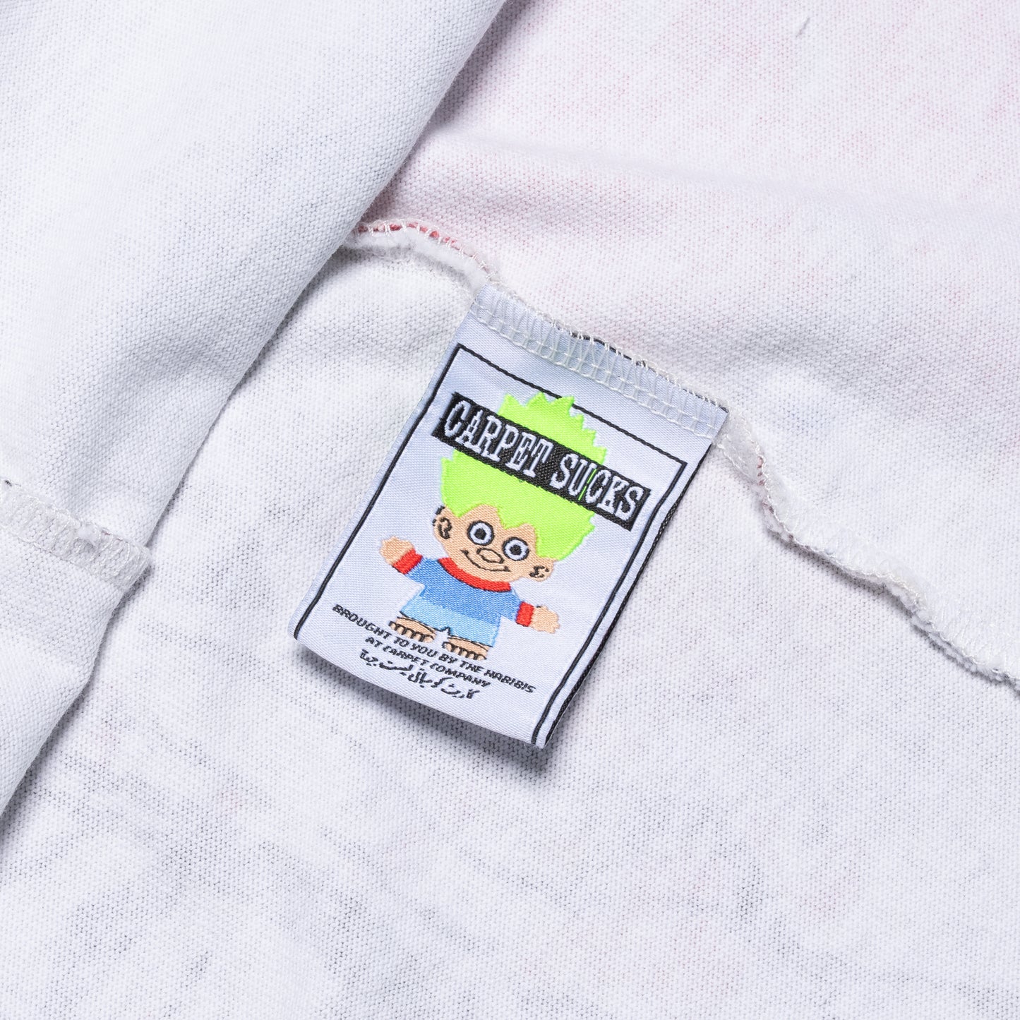 Close-up of a label with a cartoon character and text on a white fabric background