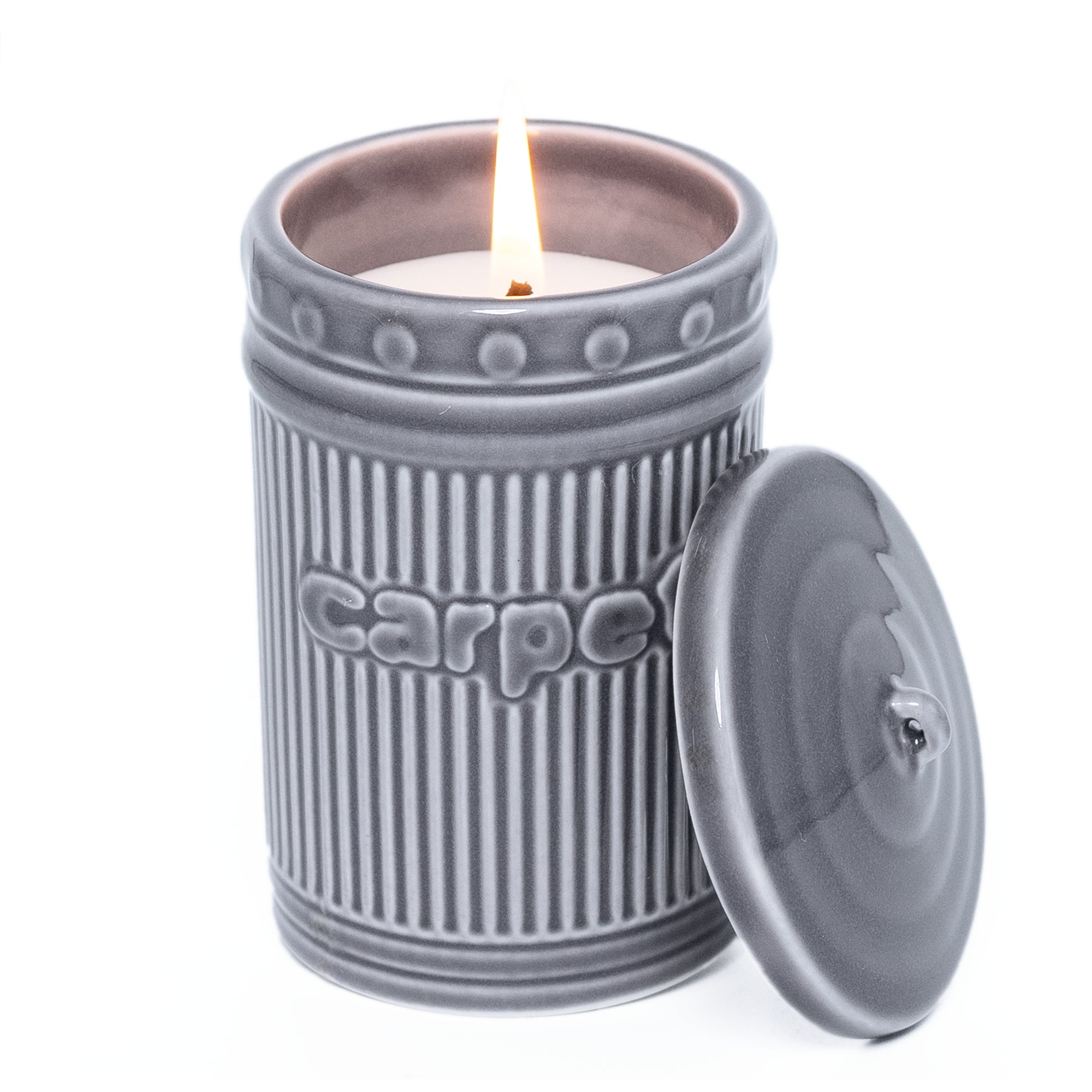 Gray ceramic candle jar with a lit candle inside on a white background