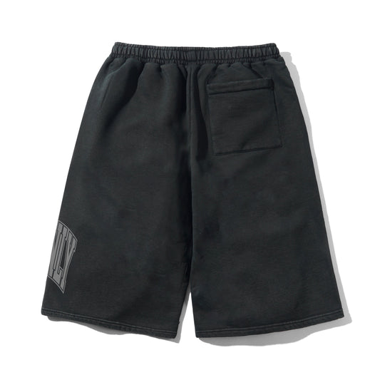 Black cotton drawstring shorts with an elastic waistband, a side pocket, and a gray graphic print on the lower left leg, shown against a plain white background.