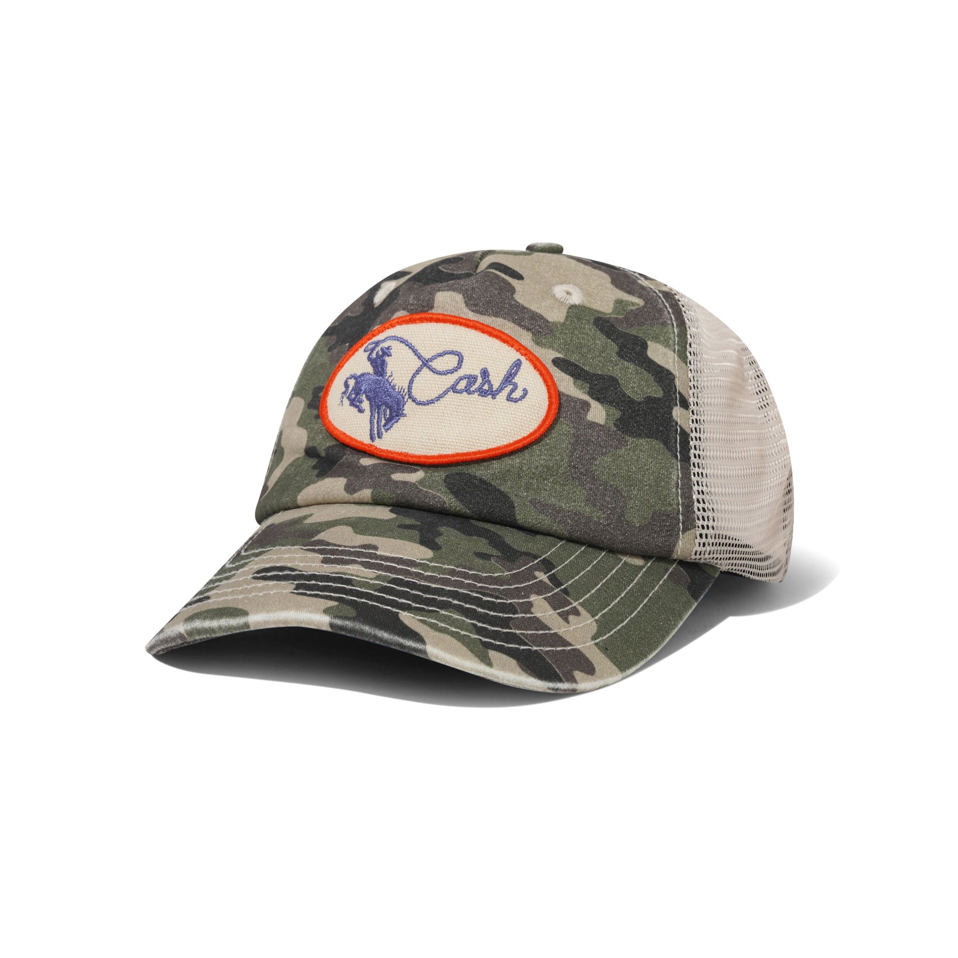 A camouflage trucker cap with a beige mesh back and a circular embroidered patch on the front featuring the brand name 'Cash' in blue with a horse logo inside an orange border.