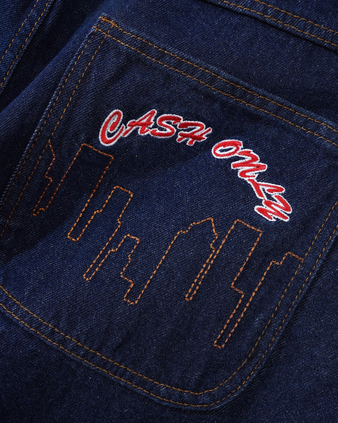 Close-up of a blue denim pocket with red and white text on a dark background