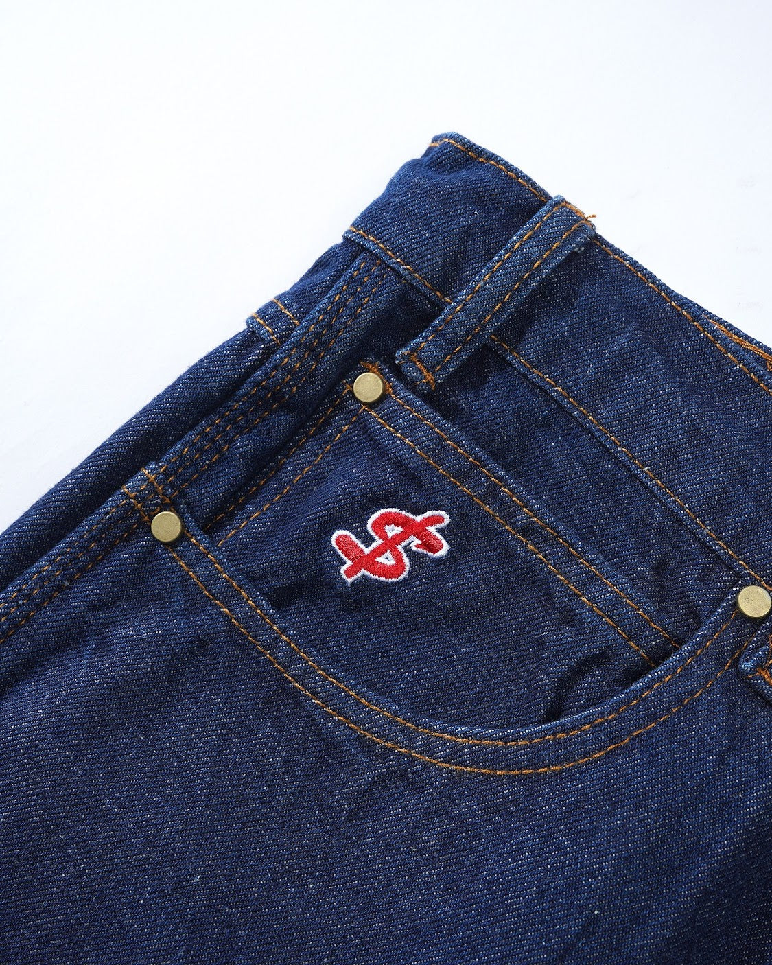 Close-up of a blue denim pocket with a red and white logo on a white background