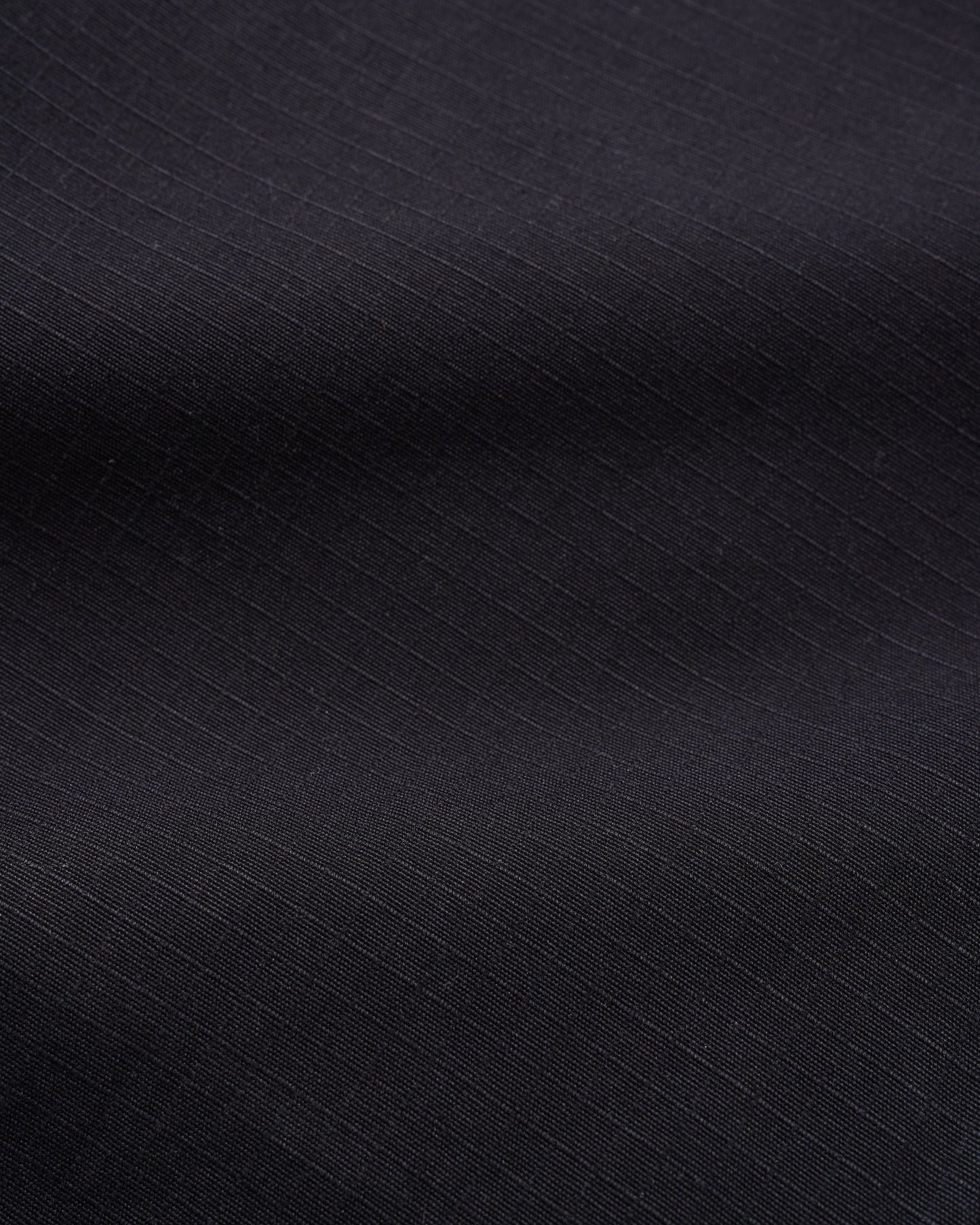 A close-up of dark charcoal gray fabric with a subtle diagonal ribbed texture.