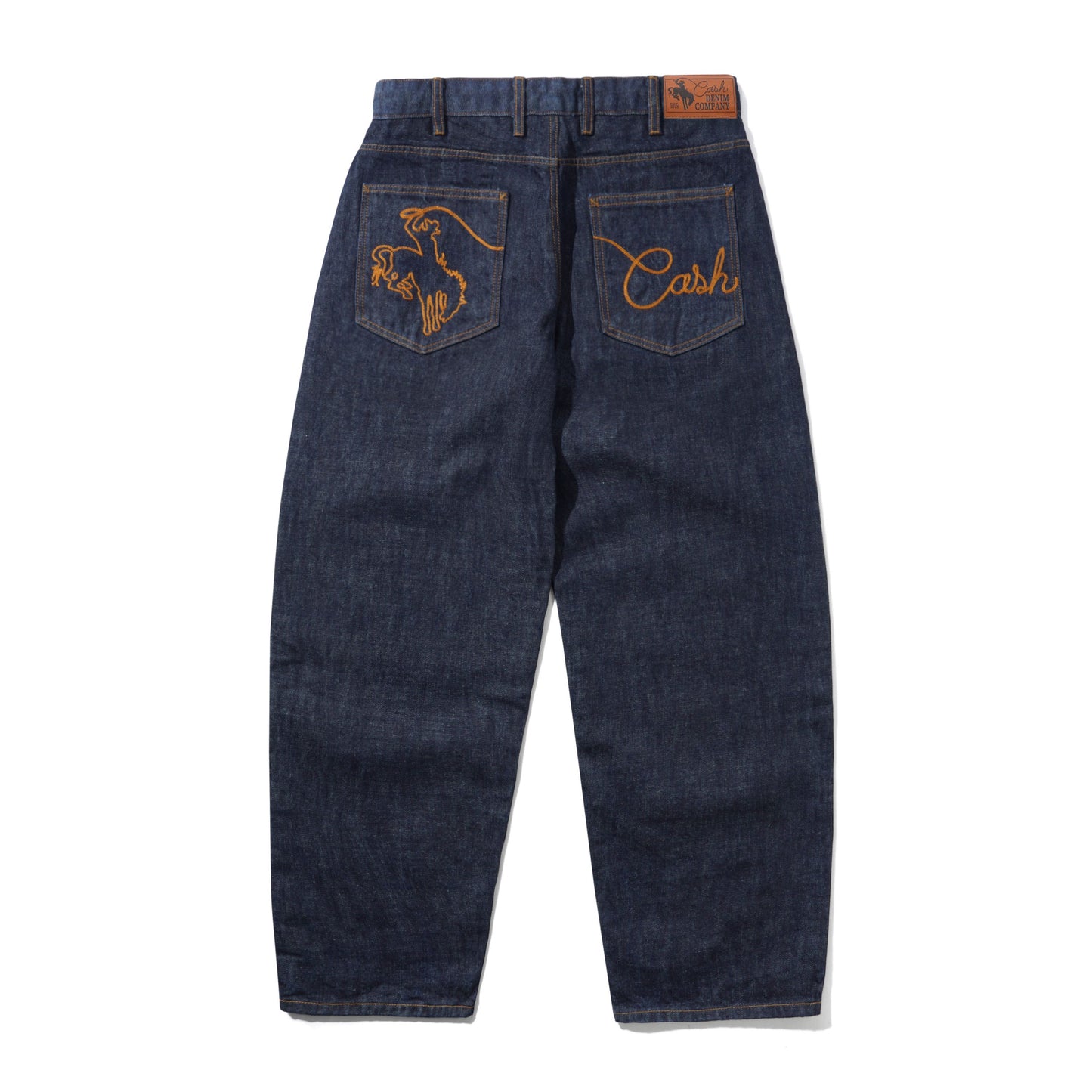 Back view of dark blue denim jeans featuring orange embroidered designs on the back pockets and a brown leather patch at the waistband, shown on a white background.