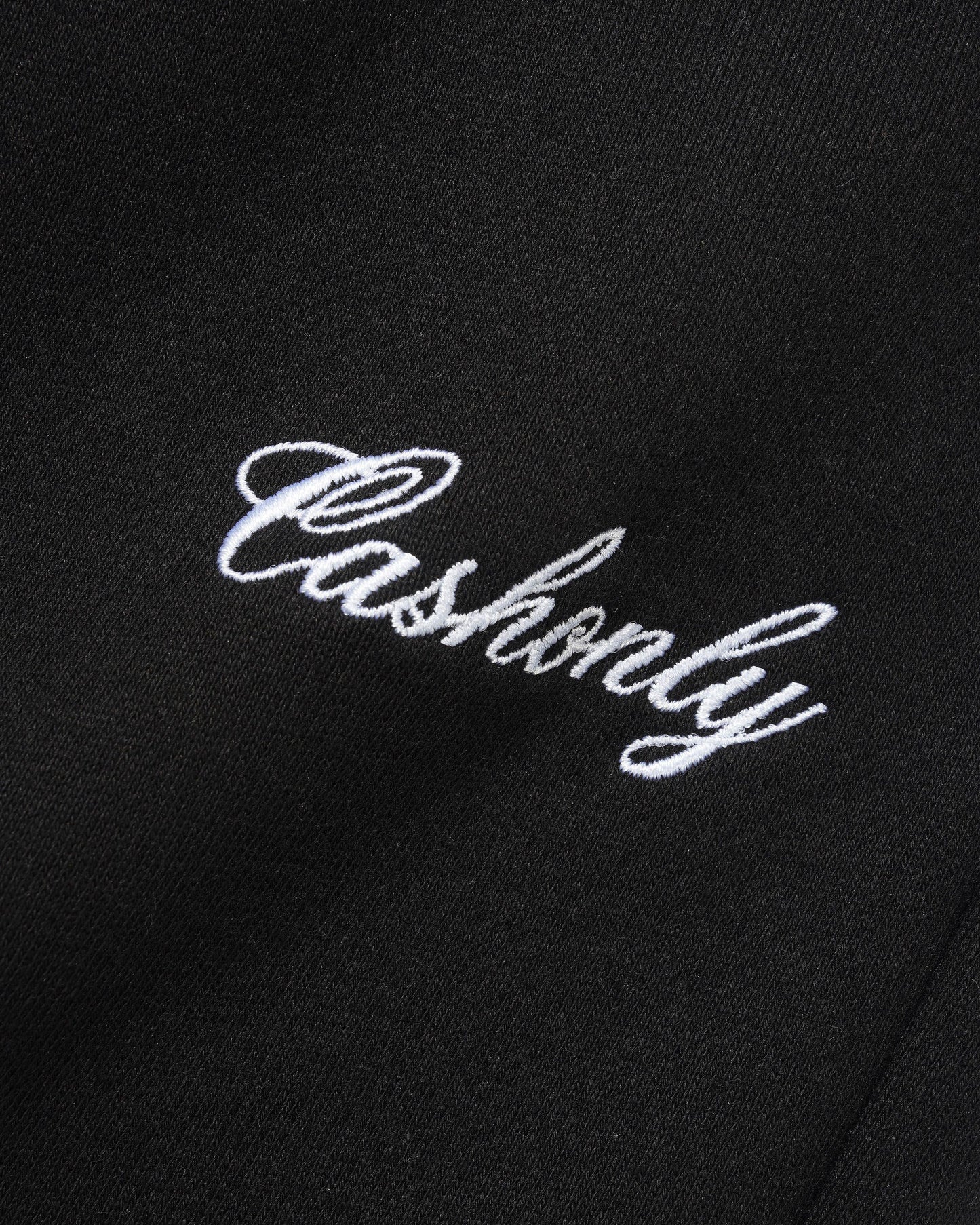Close-up of a black fabric surface with white embroidered script reading 'Cashionly'.