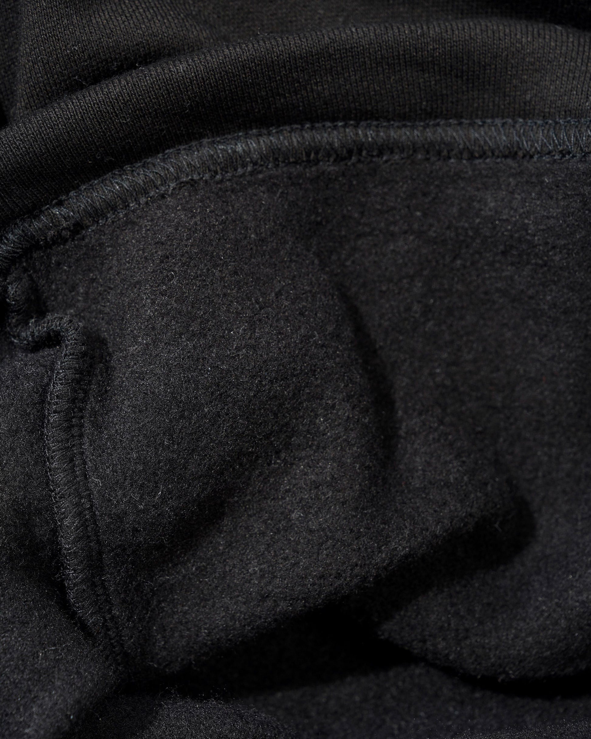 Close-up of a black fabric garment showing the texture of the material and a stitched seam.