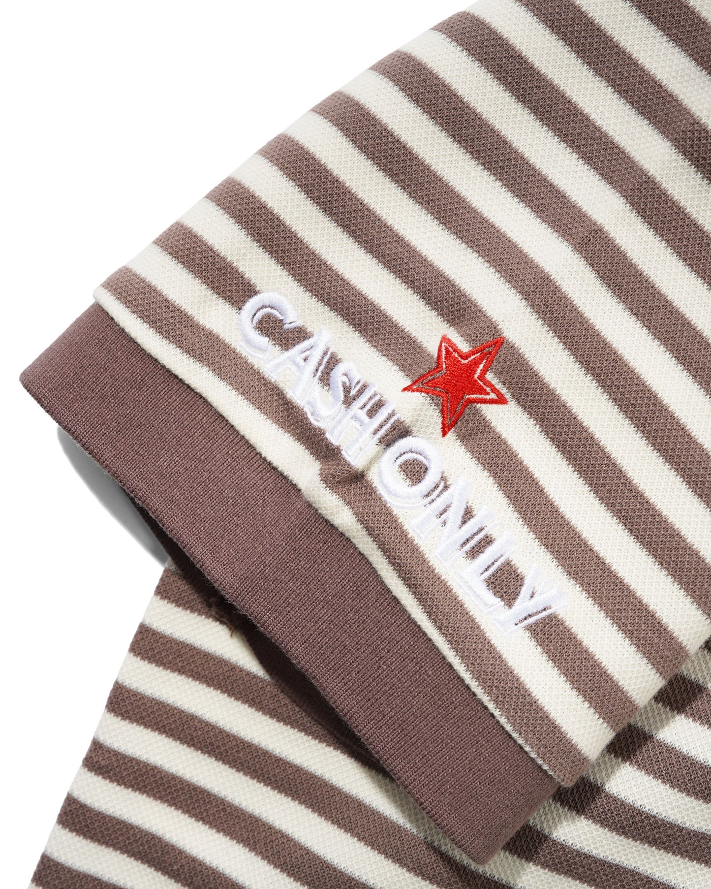 Close-up of a striped knit garment, likely a sweater or scarf, in brown and cream with white embroidered text reading 'CASH ONLY' and a red star accent.