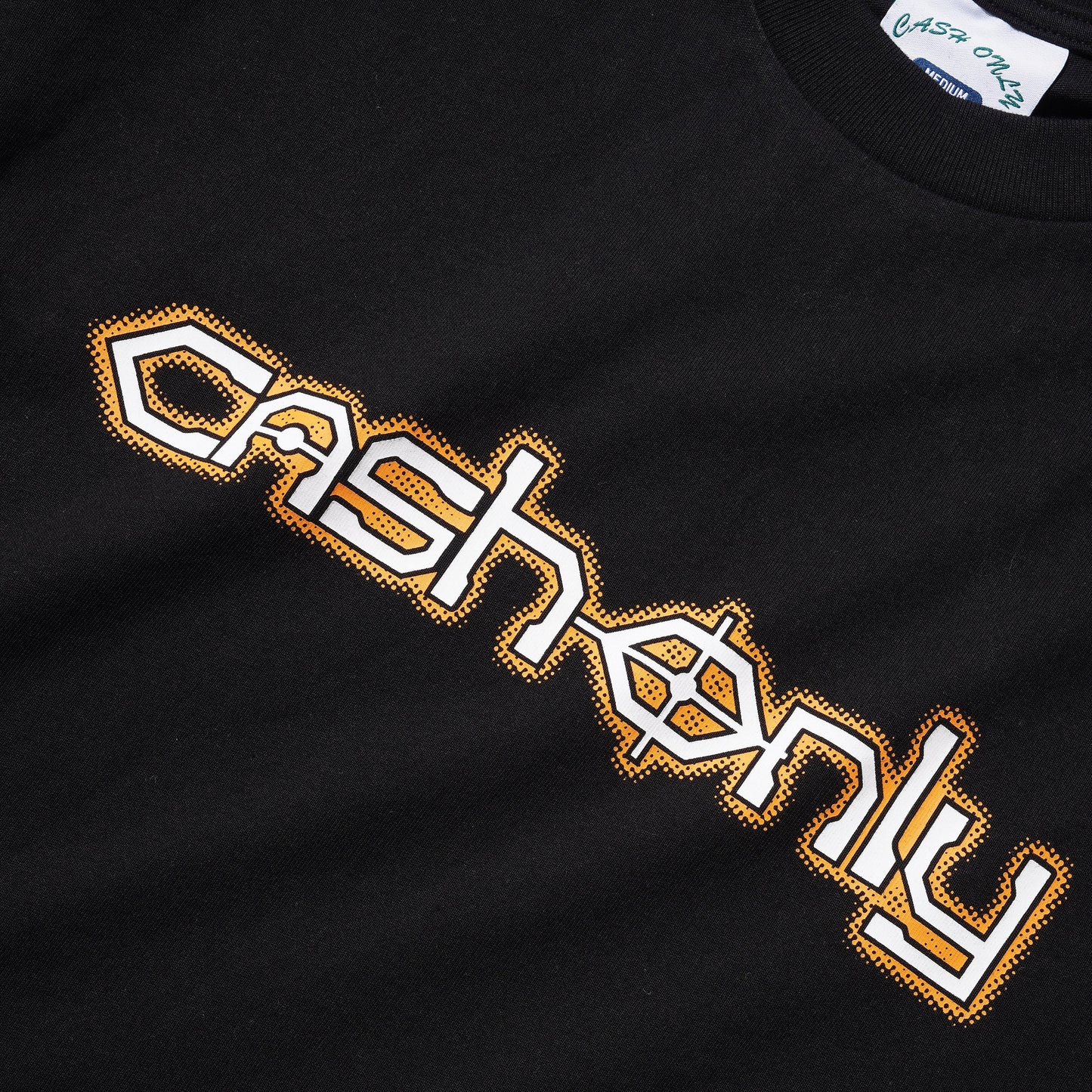 Close-up of a black t-shirt featuring a stylized 'cash only' graphic in white with a gold outline across the chest.