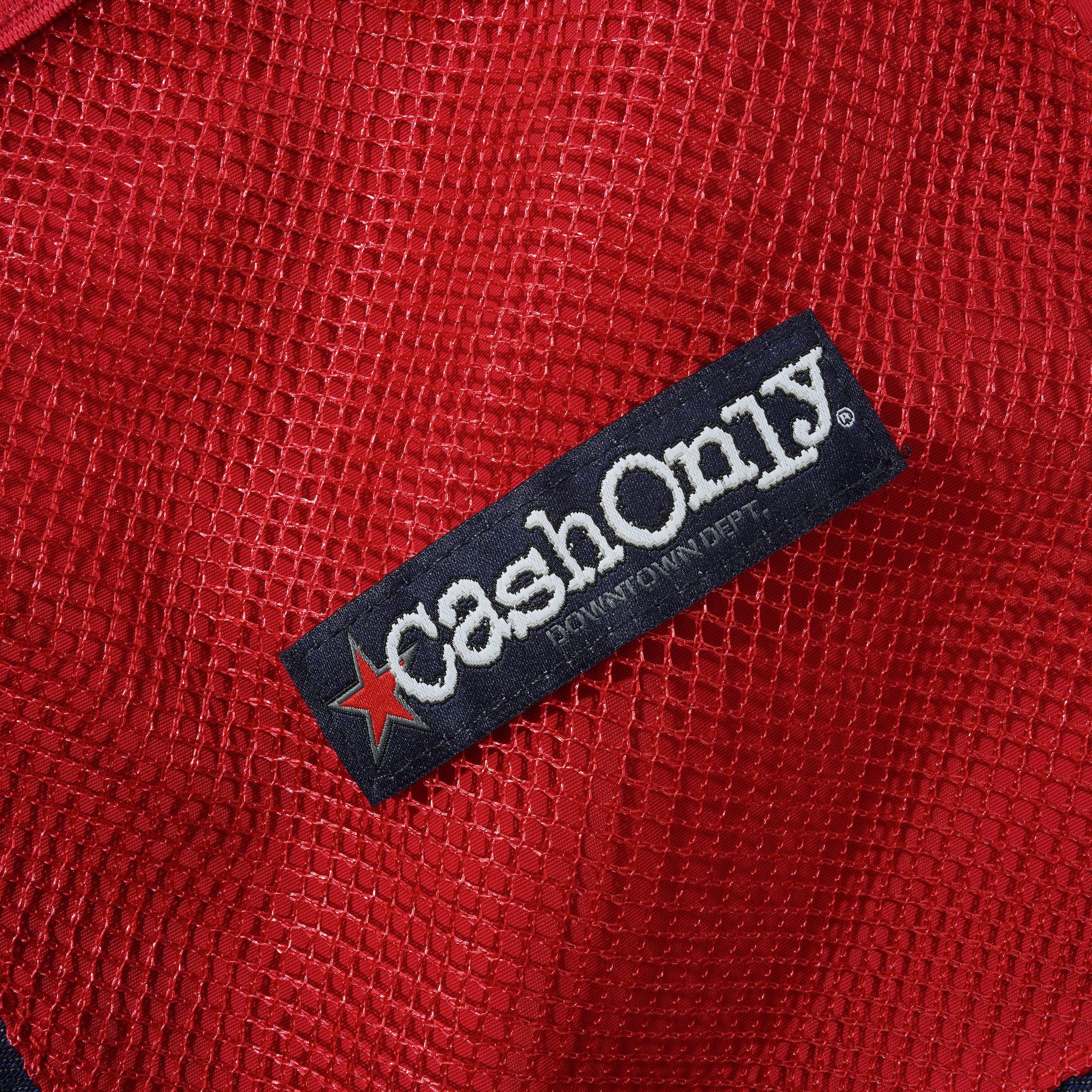 Close-up of a red mesh fabric item with a black fabric brand label reading CashOnly and featuring a red star logo.