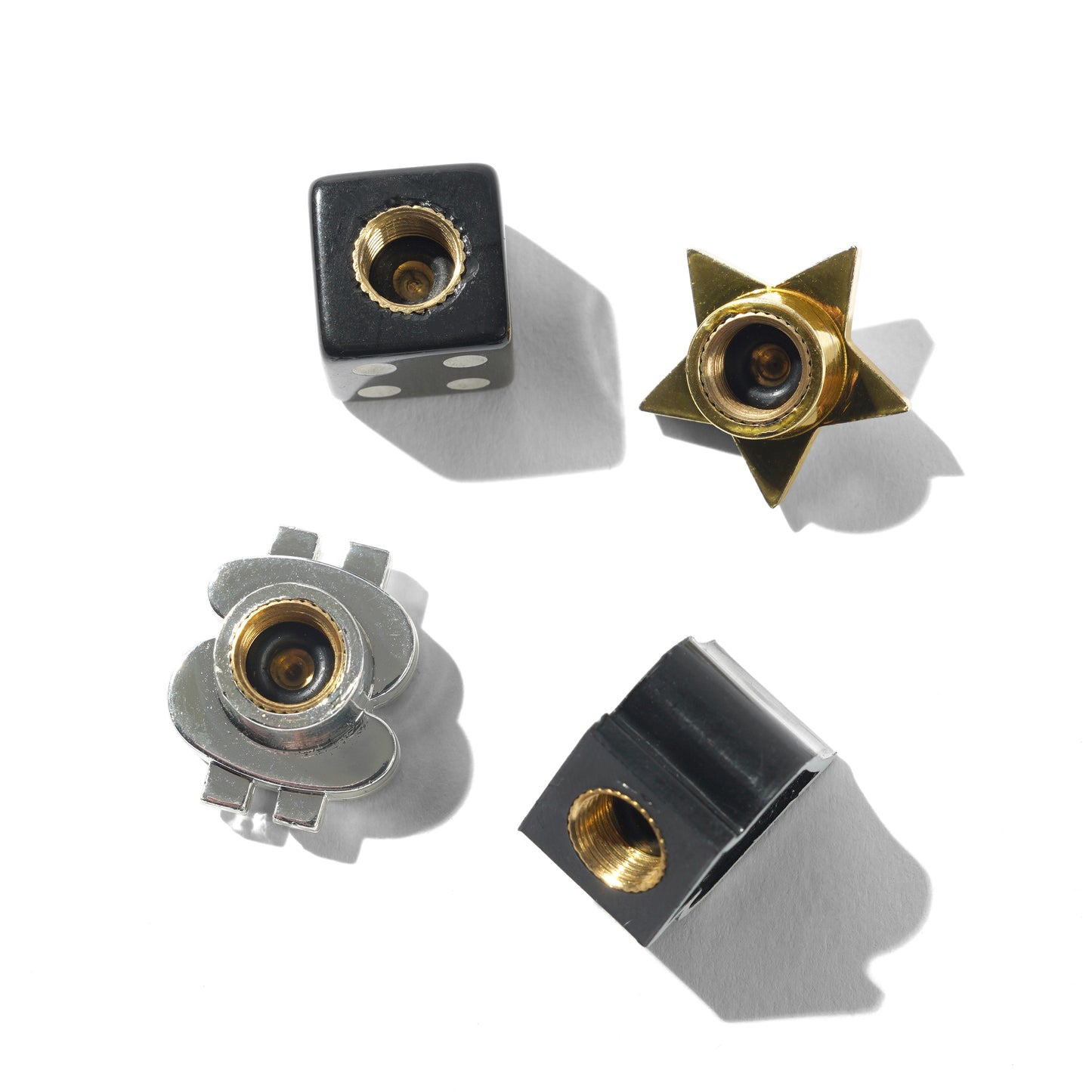 Four metal valve caps with gold and black finishes on a white background