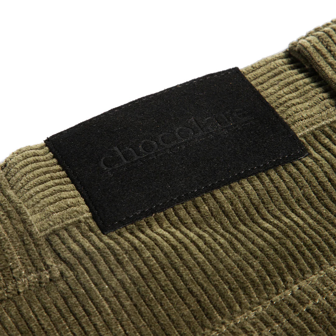 Close-up of a green corduroy fabric with a black label on a white background
